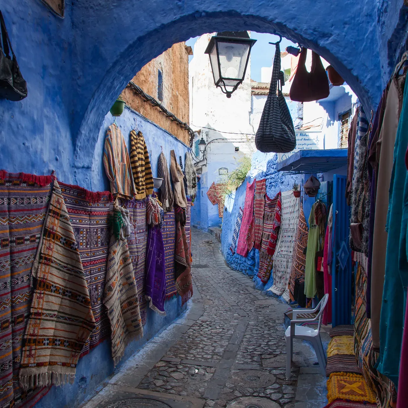 Chefchaouen Medina blue alley with local artisans and colorful textiles